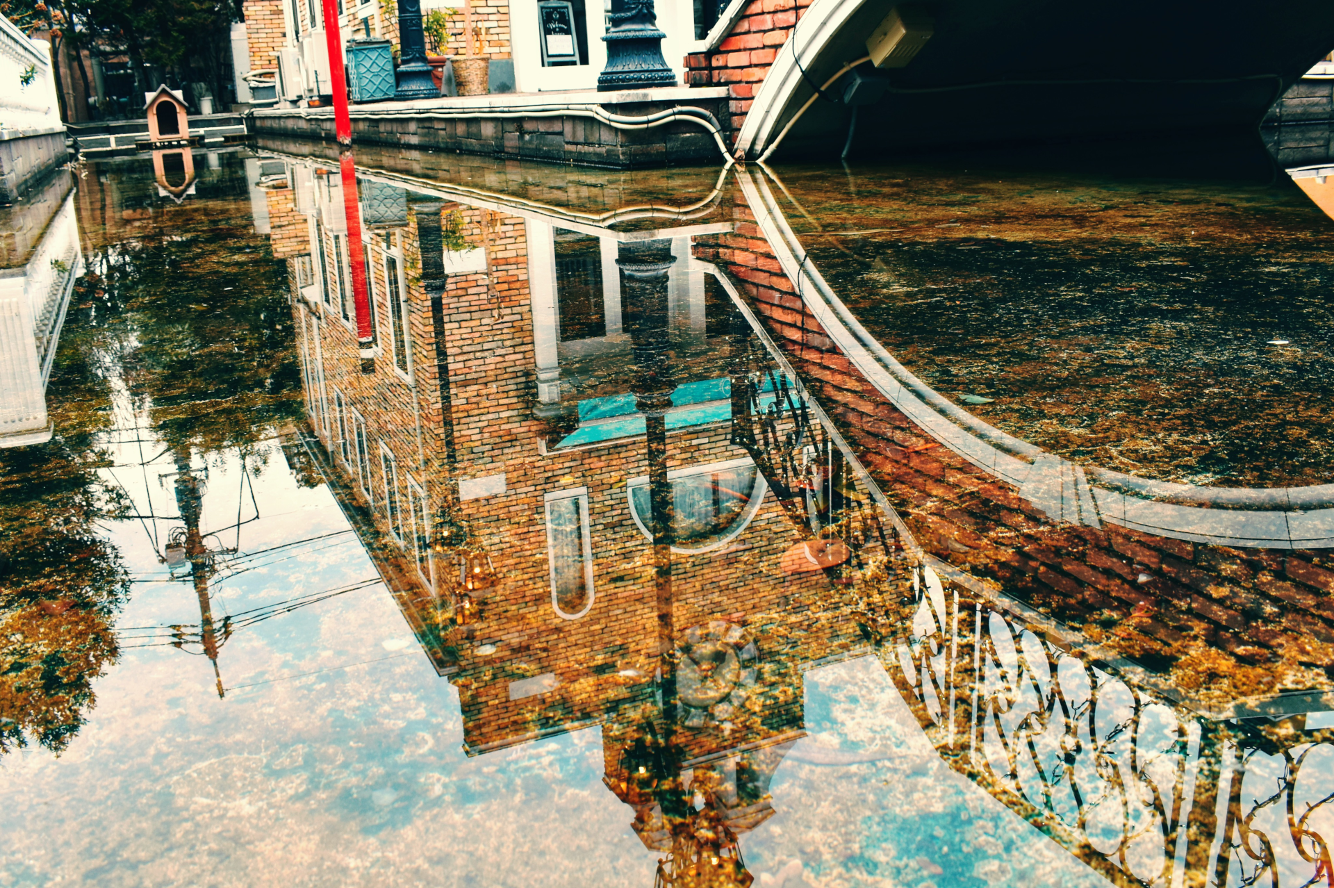 The reflection of a brick building and bridge in shallow water