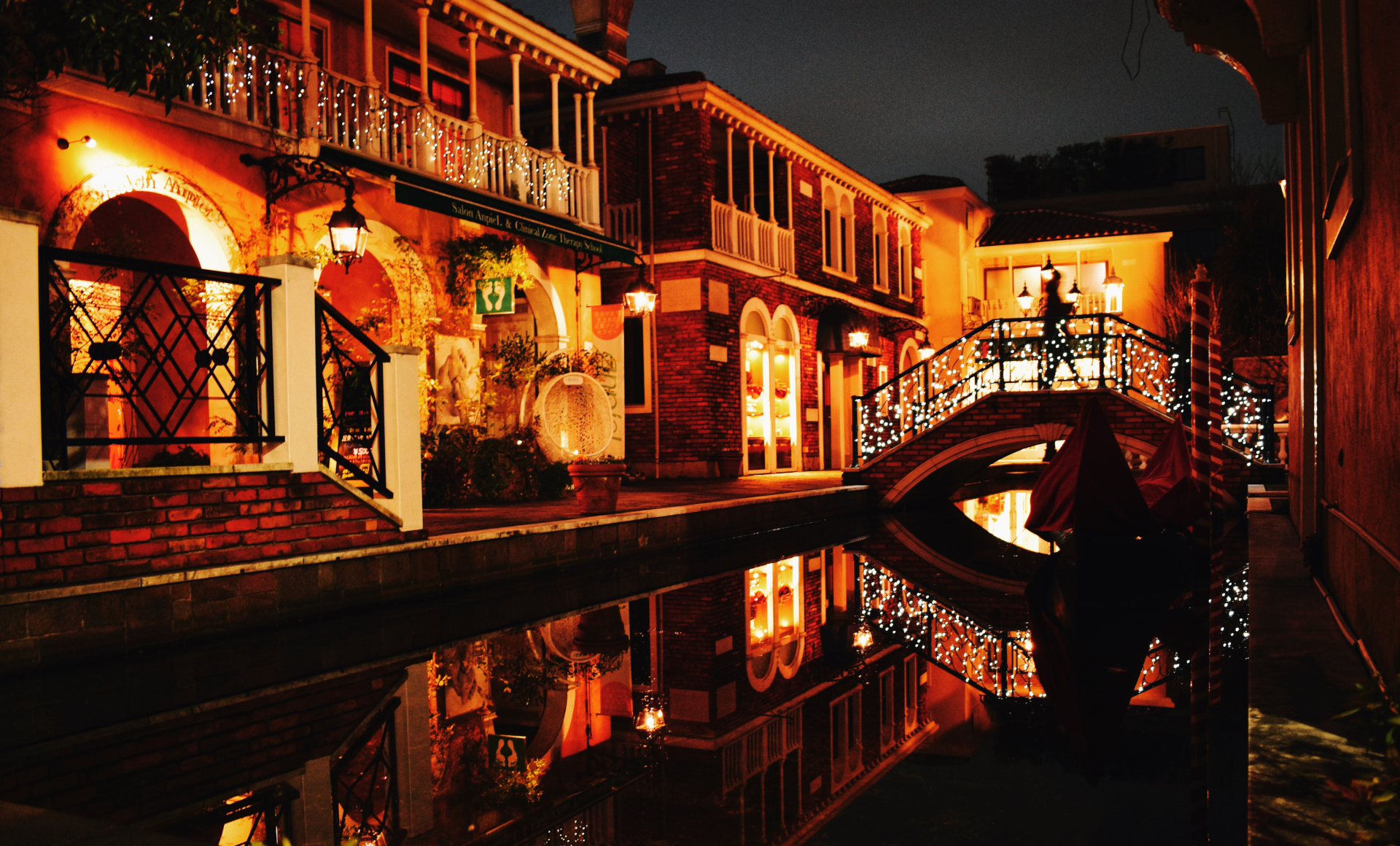 Photo of houses with warm outdoor lighting by a canal